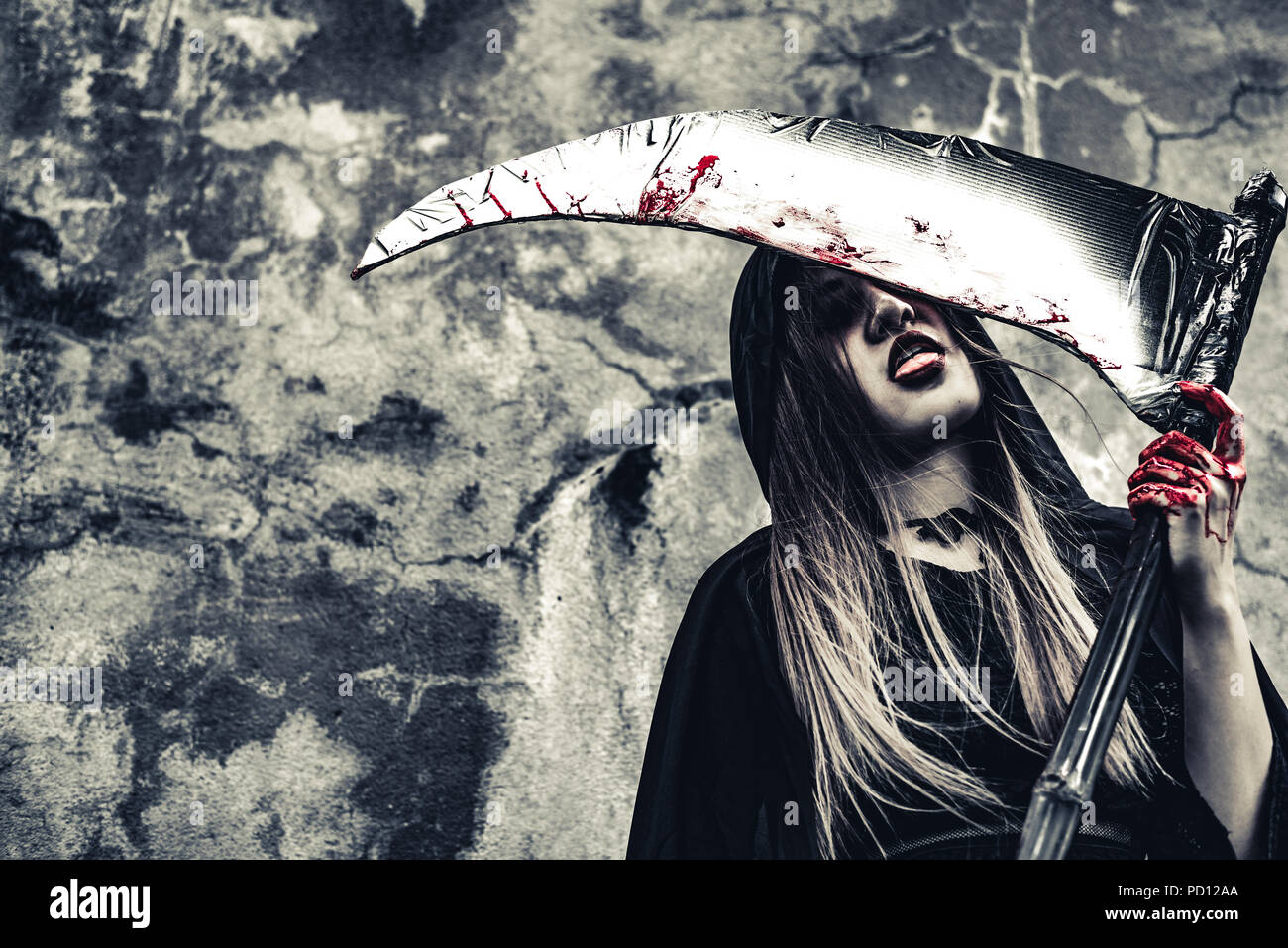 Demon witch leccare il sangue su reaper. Demone femminile angelo vestiti di nero e il cofano sulla parete grunge background. Il giorno di Halloween e il mistero del concetto. Fantas Foto Stock