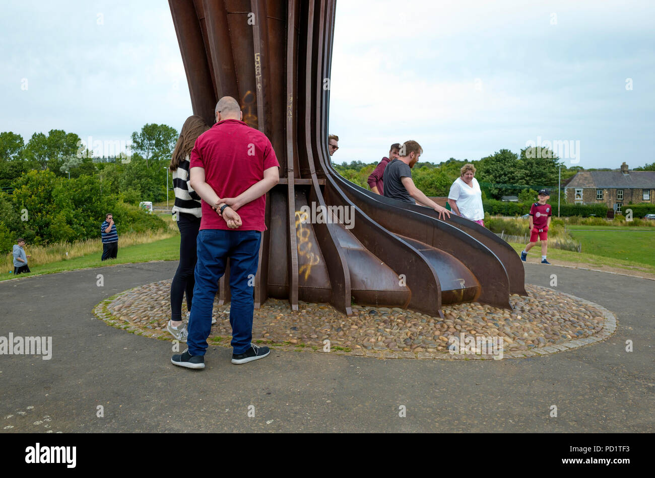 Un gruppo di persone ai piedi del massiccio di angelo del Nord la scultura da Anthony Gormley a Gateshead dando scala Foto Stock