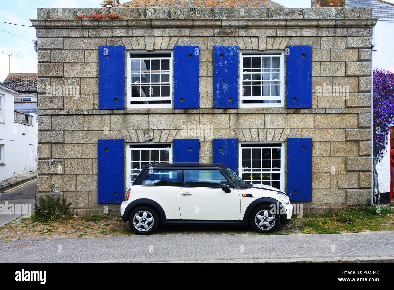 In stile retrò mini parcheggiato di fronte a un vecchio edificio in granito, Marazion, Cornwall, Regno Unito - Giovanni Gollop Foto Stock