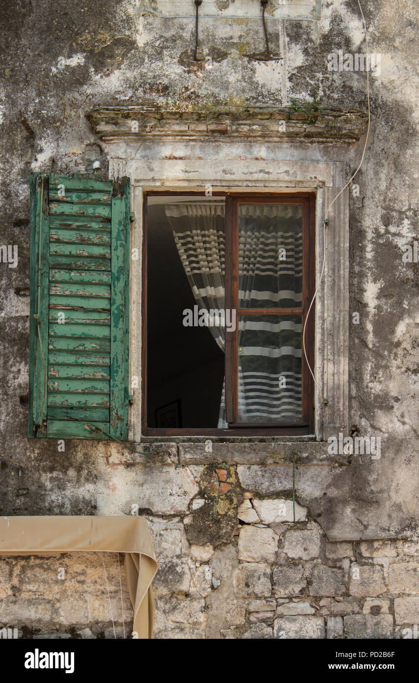 Un finestrino chiuso con ante di una casa di pietra Foto Stock