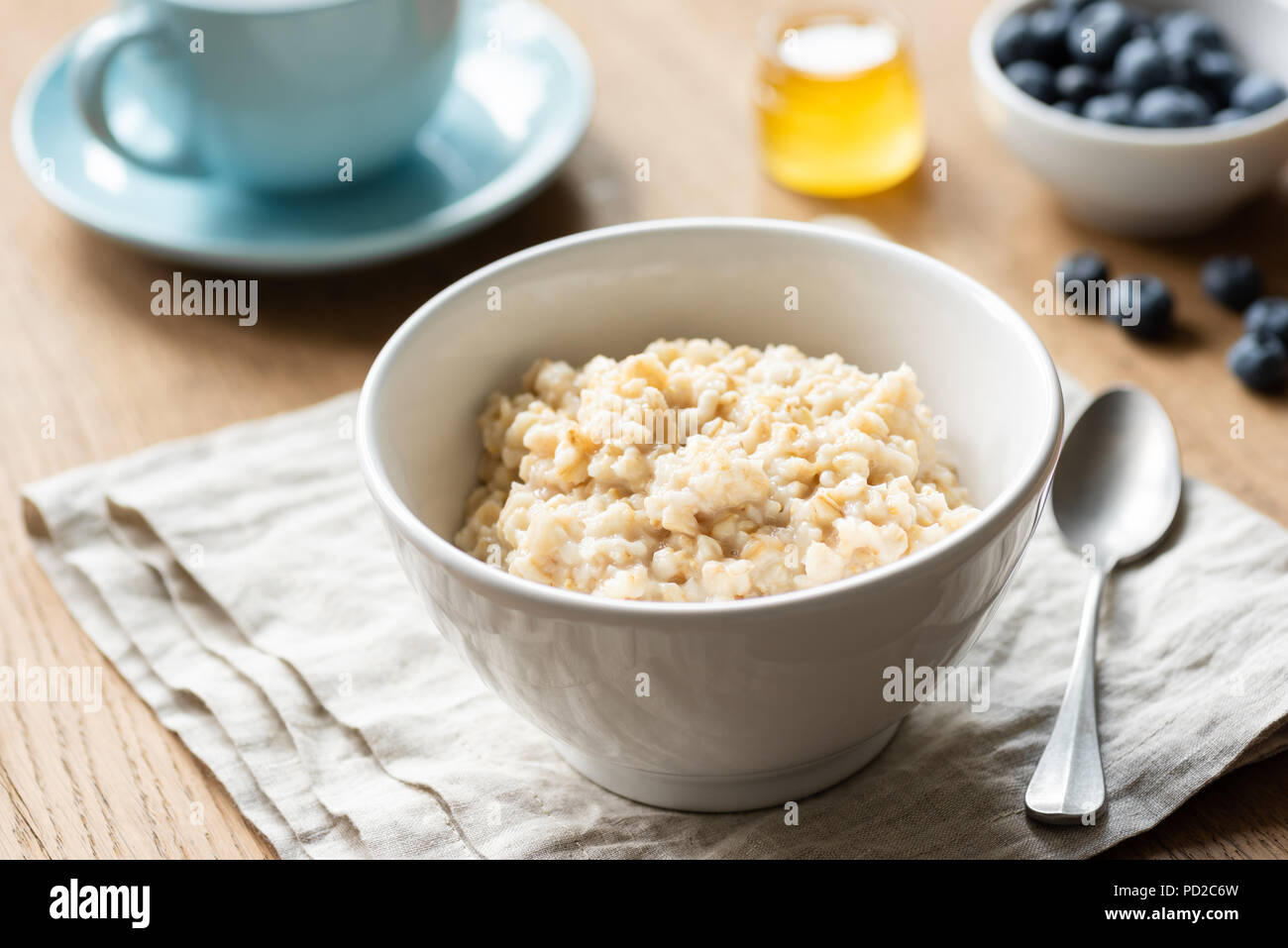 Porridge di fiocchi d'avena, scozzese di avena in una ciotola sul tavolo, biancheria da cucina. Una sana prima colazione, uno stile di vita sano concetto Foto Stock