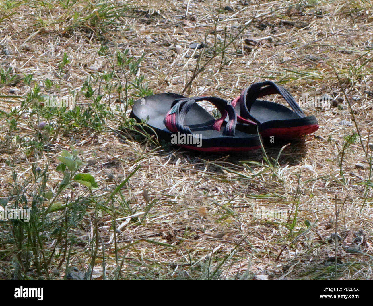 Una coppia di uomini flip flop vicino a terra vicino al bordo delle acque Foto Stock
