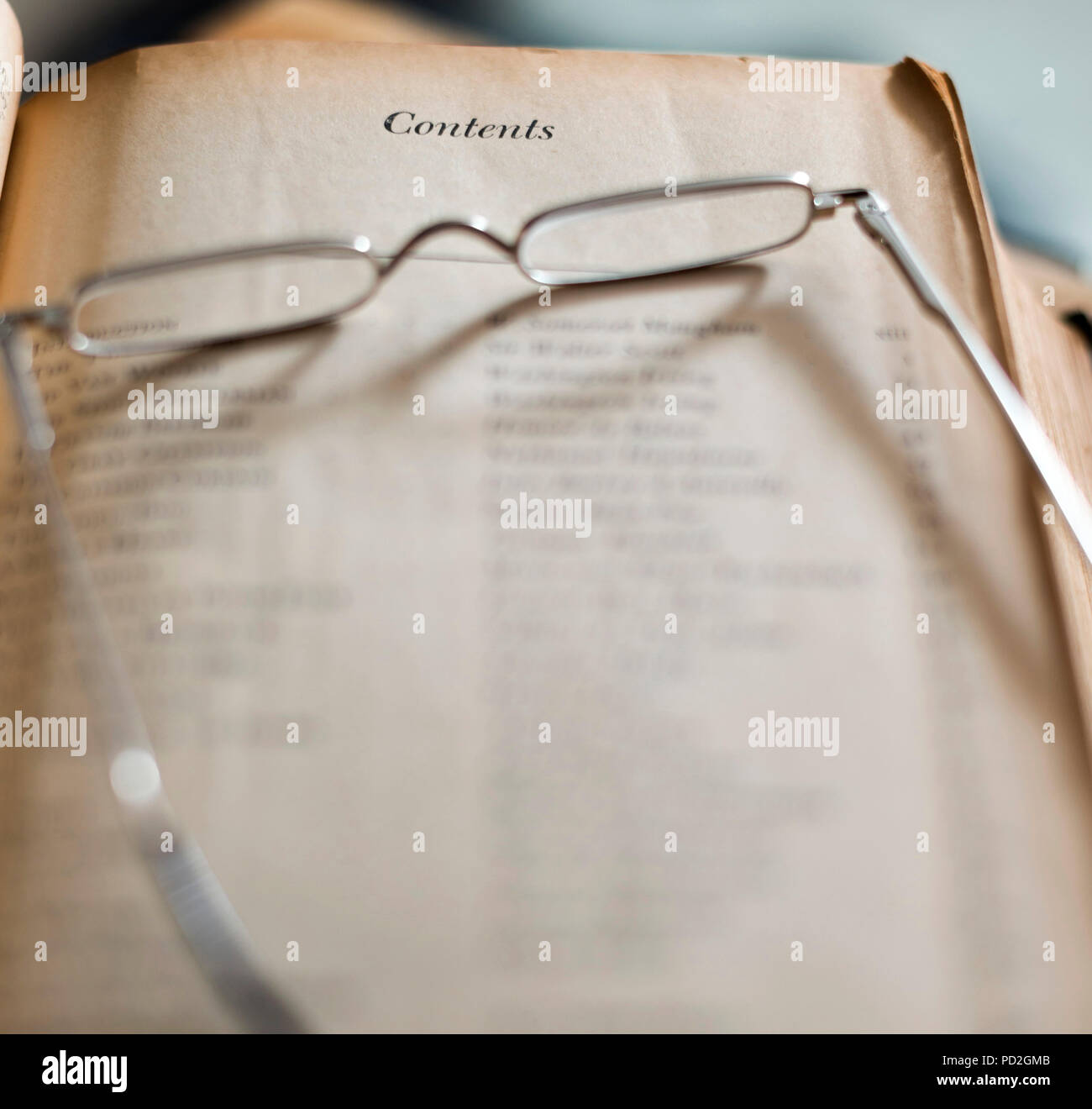 Vecchio libro con contenuti nella tabella e gli occhiali da lettura Foto Stock