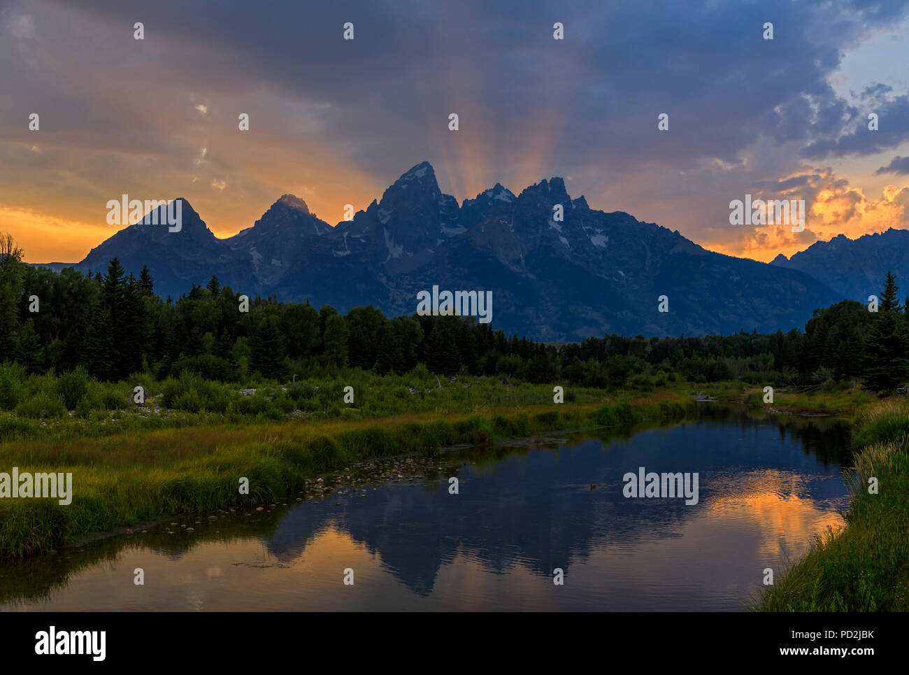 In questa vista i raggi di luce dal sole al tramonto scatta verso l'alto sopra le cime del Teton gamma della montagna nel Parco Nazionale di Grand Teton, Wyoming USA Foto Stock