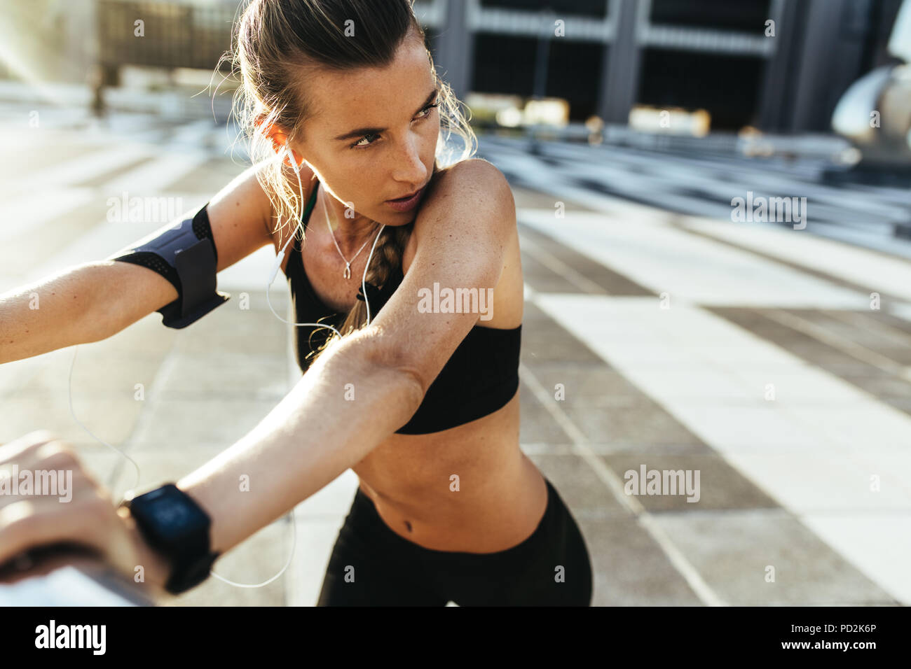Atleta donna in allenamento che si allena la mattina indossando gli auricolari. donna che fa esercizi di stretching prima della corsa mattutina. Foto Stock