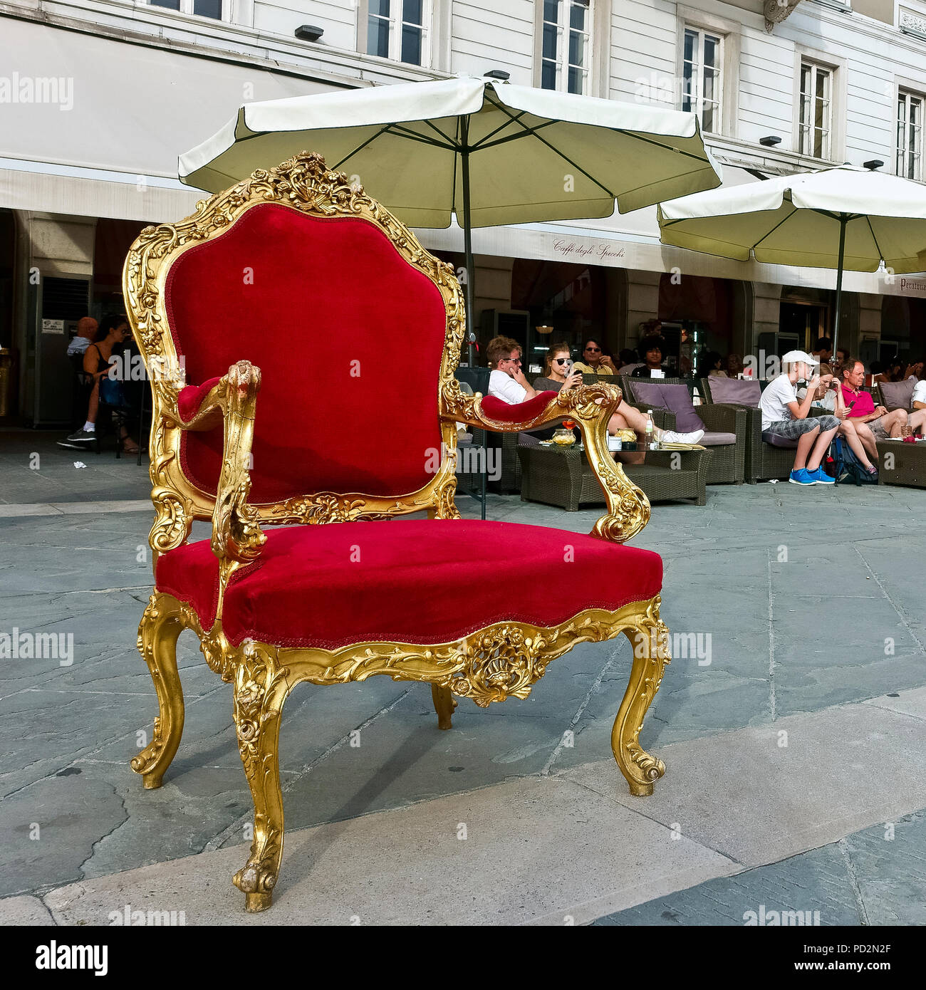 Velluto rosso e oro imperatore trono poltrona, vuota sulla pavimentazione della piazza dell'Unità d'Italia, al di fuori di Caffè degli Specchi. Trieste, Italia, Europa. Foto Stock