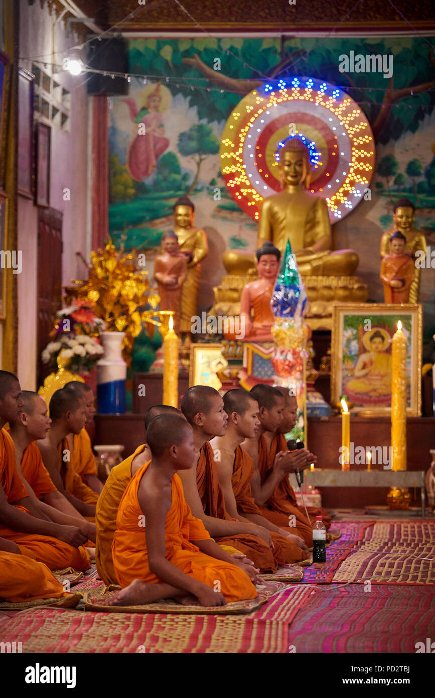 Un gruppo di giovani monaci buddisti seduto a terra durante una cerimonia in uno dei santuari nel loro monastero. In Siem Reap, Cambogia. Foto Stock