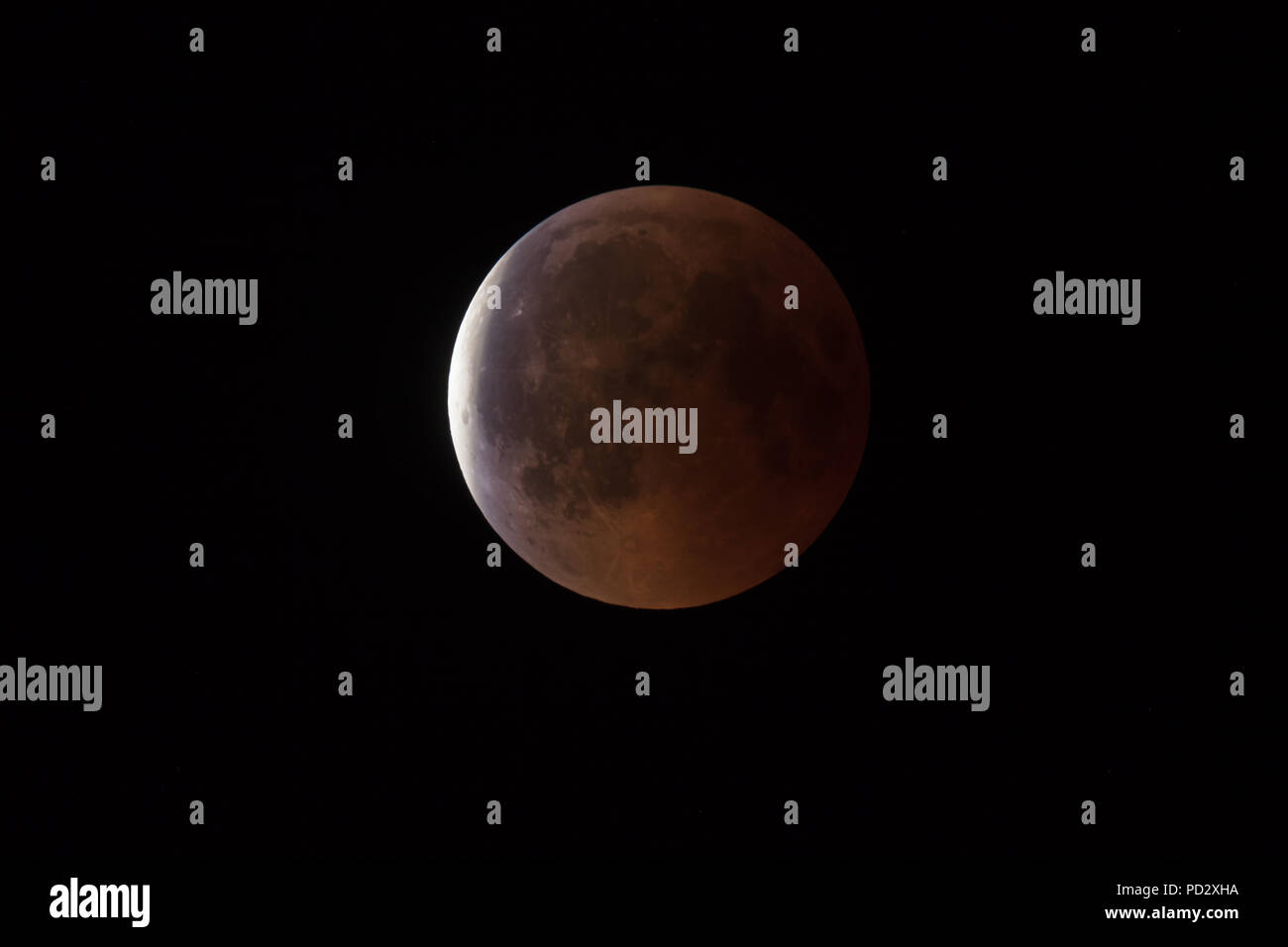 Super sanguinosa luna piena di eclipse fase finale contro il cielo nero sfondo, Terra ombra di iniziare a spostare fuori dalla superficie della luna Foto Stock