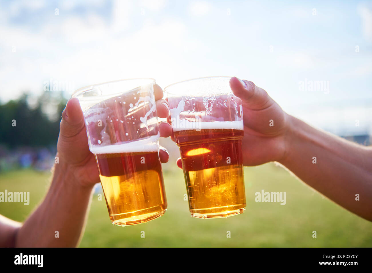 Due giovani amici maschi fare un brindisi con bicchieri di birra a Holi festival Foto Stock