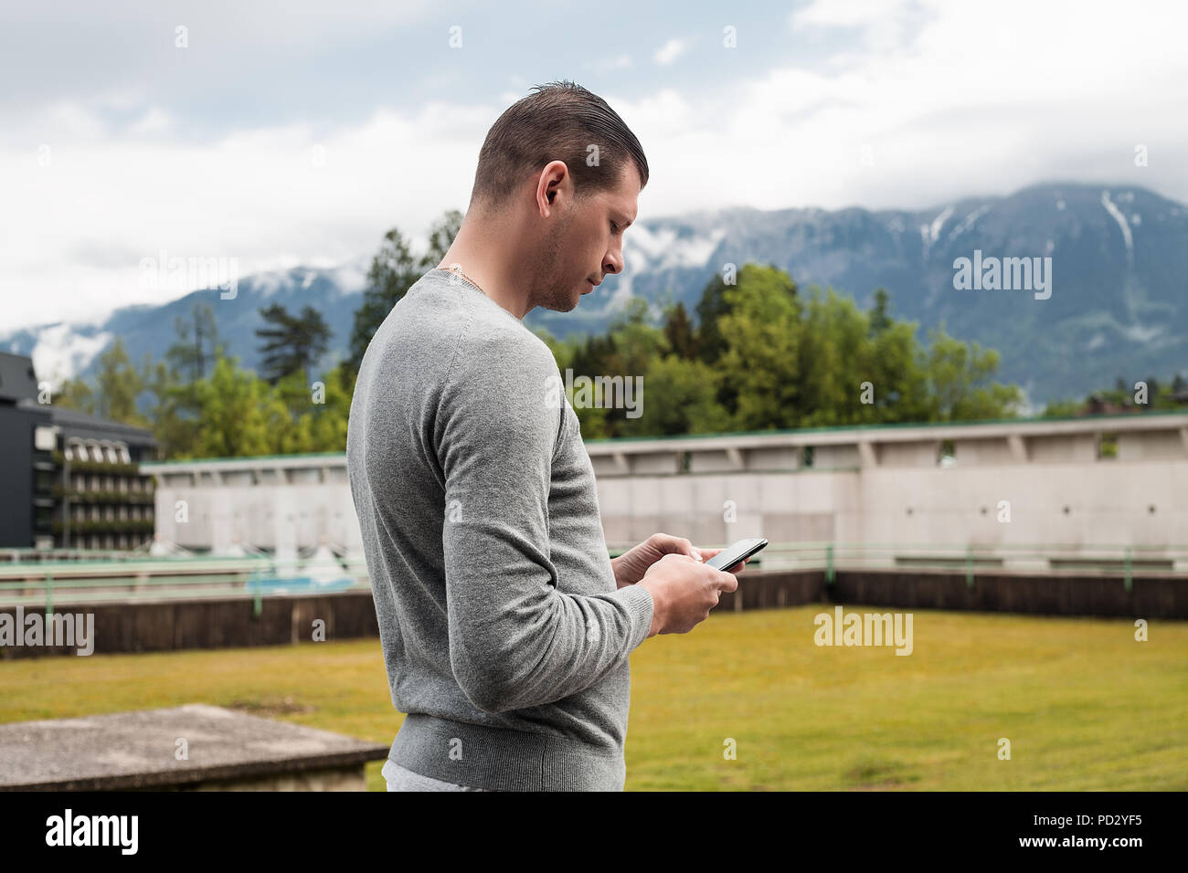 Uomo che guarda lo smartphone nel villaggio di montagna, Dolenci, Slovenia Foto Stock