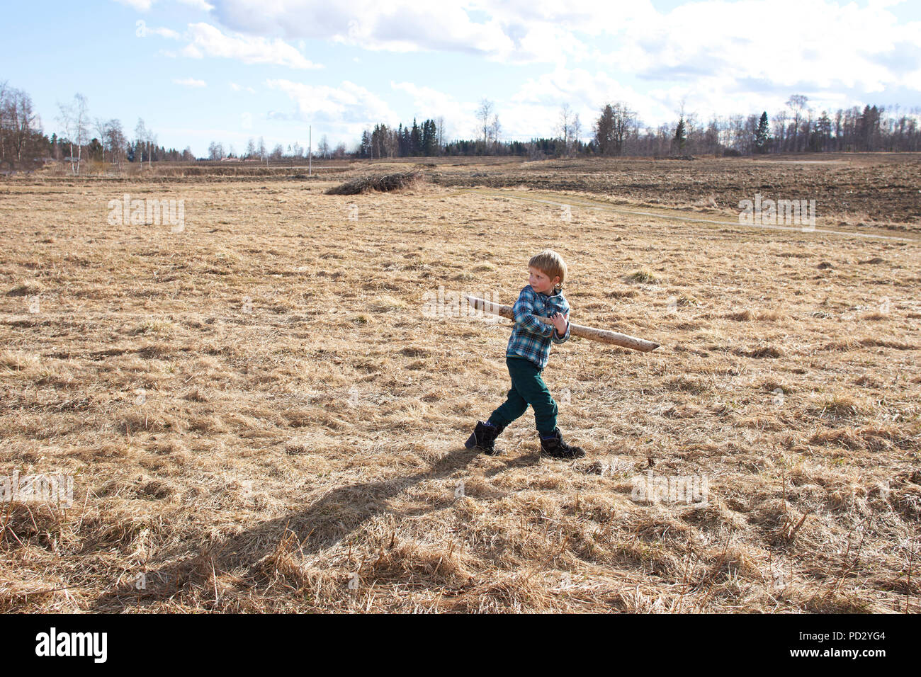 Ragazzo che trasportano palo di legno sul campo Foto Stock