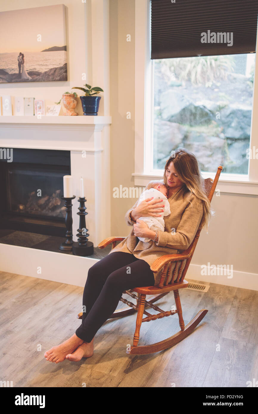 Madre seduto nella sedia a dondolo holding neonato boy Foto stock - Alamy