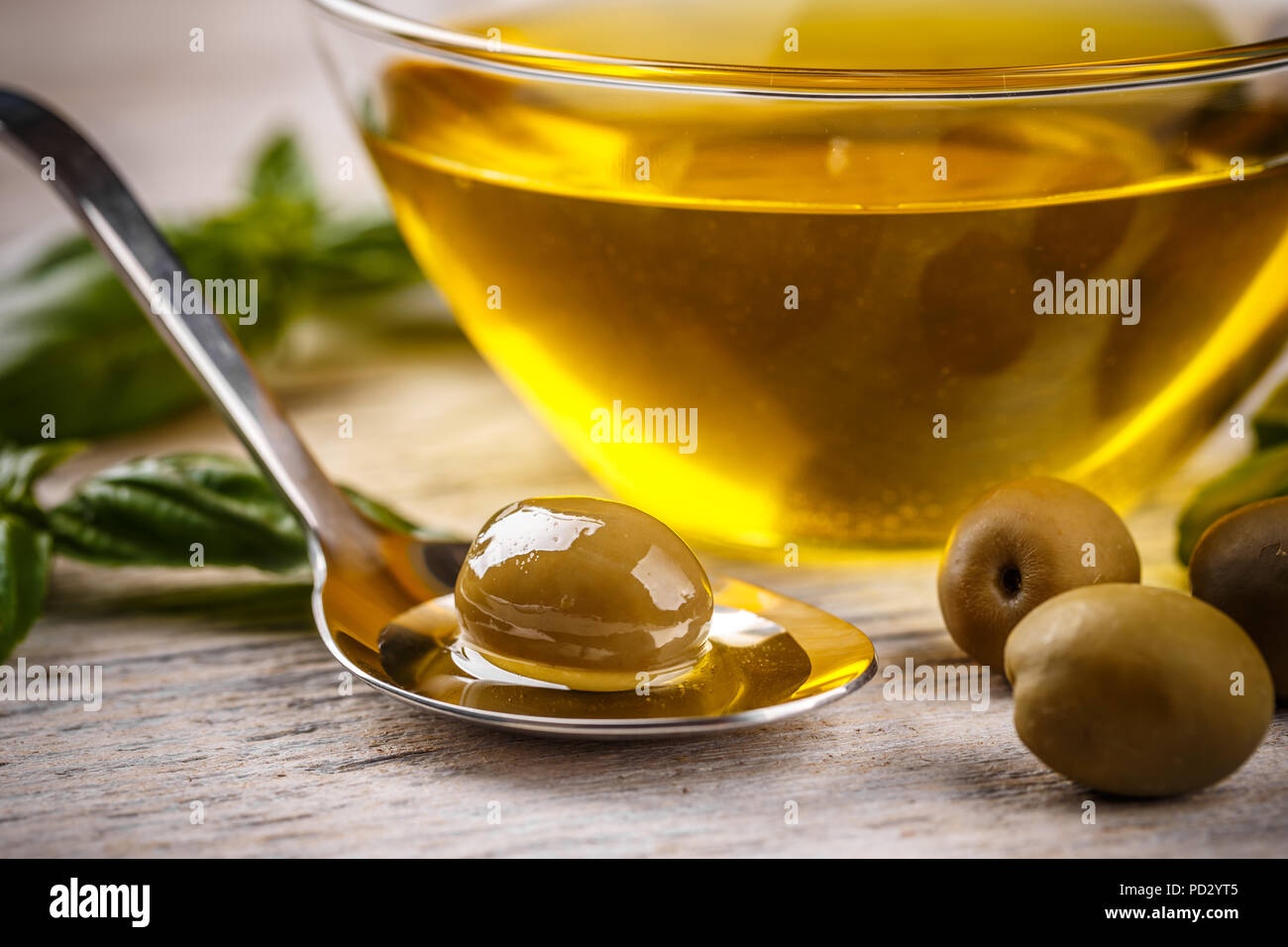 Olive in cucchiaio e olio d'oliva sullo sfondo Foto Stock