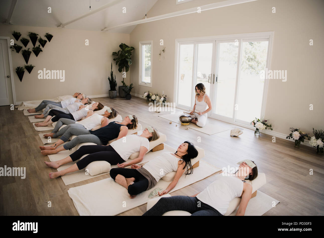 Le donne in posa di rilassamento dopo la lezione di yoga al ritiro Foto Stock