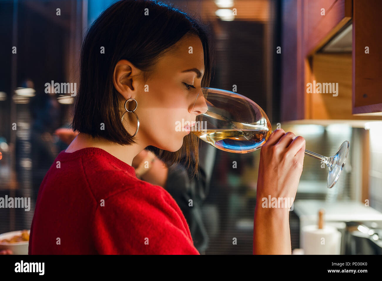 Donna bevendo vino in festa in appartamento Foto Stock