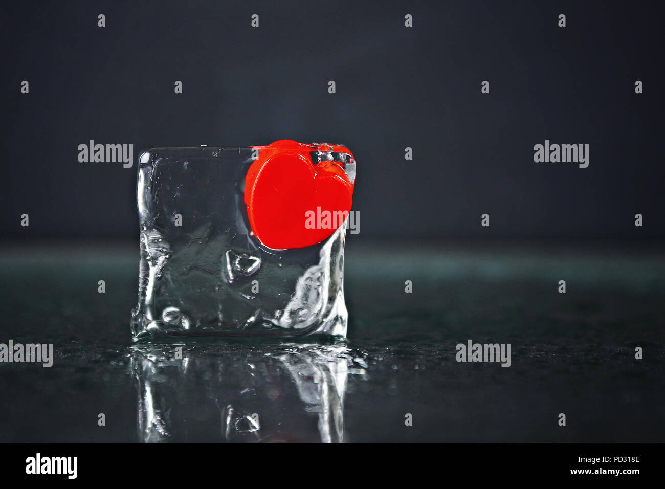 Un piccolo cuore rosso congelato in un cubetto di ghiaccio. Ghiaccio fondente, acqua Foto Stock