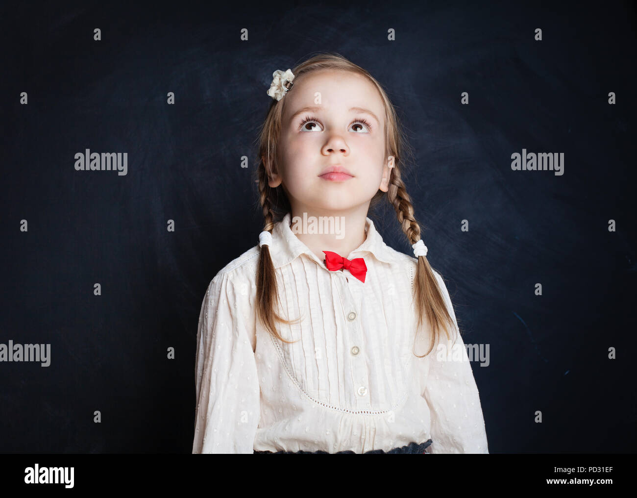 Carino bambina cercando su sfondo blackboard Foto Stock