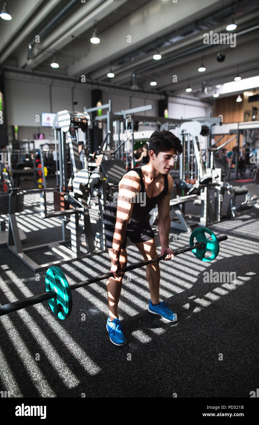 Montare il giovane uomo in palestra a lavorare fuori, sollevamento barbell. Foto Stock
