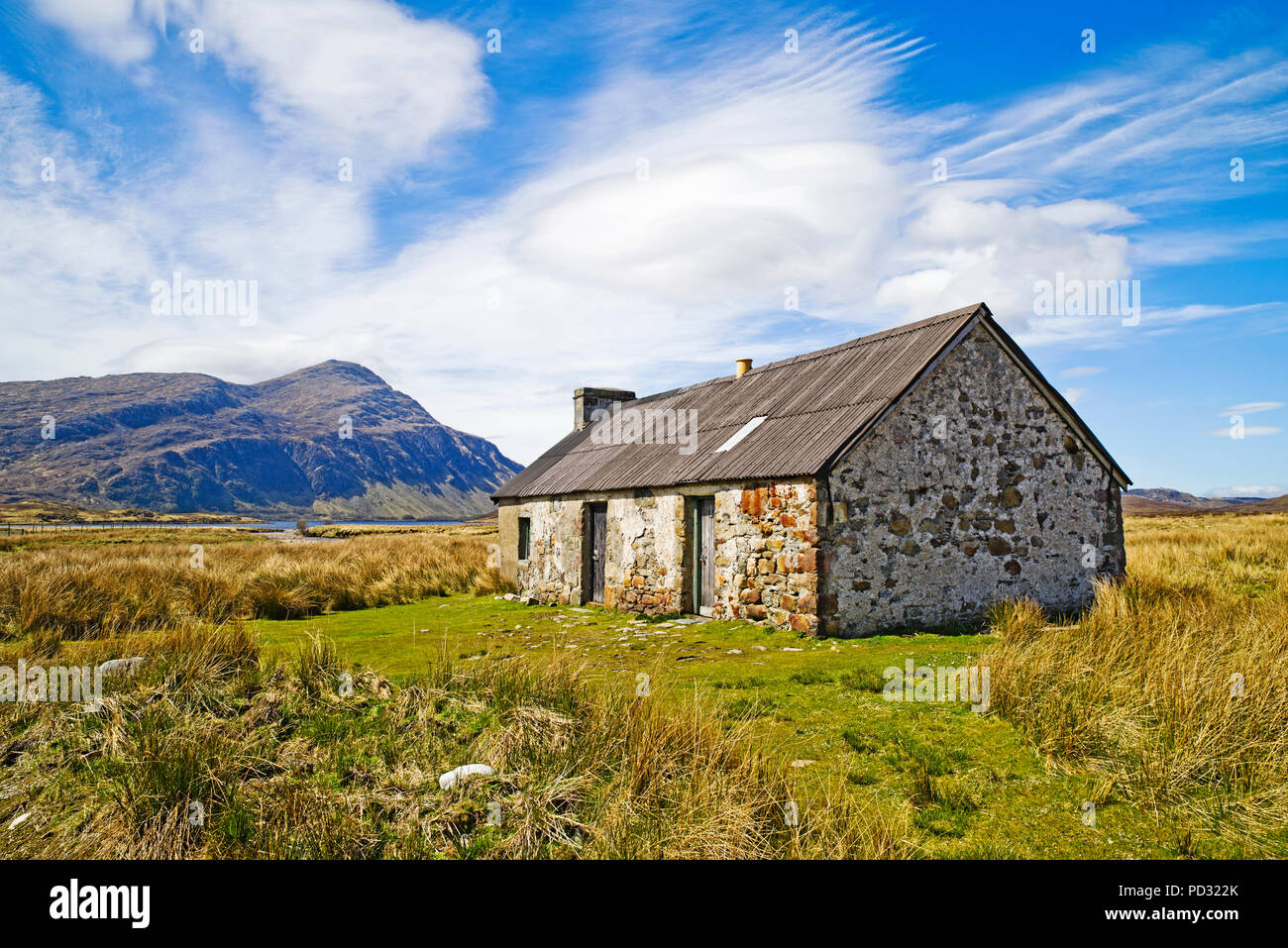 Vecchia capanna tradizionale in remoto la posizione brughiera, Sutherland, Highlands scozzesi, montagna di Ben pila in background, Scozia UK. Foto Stock