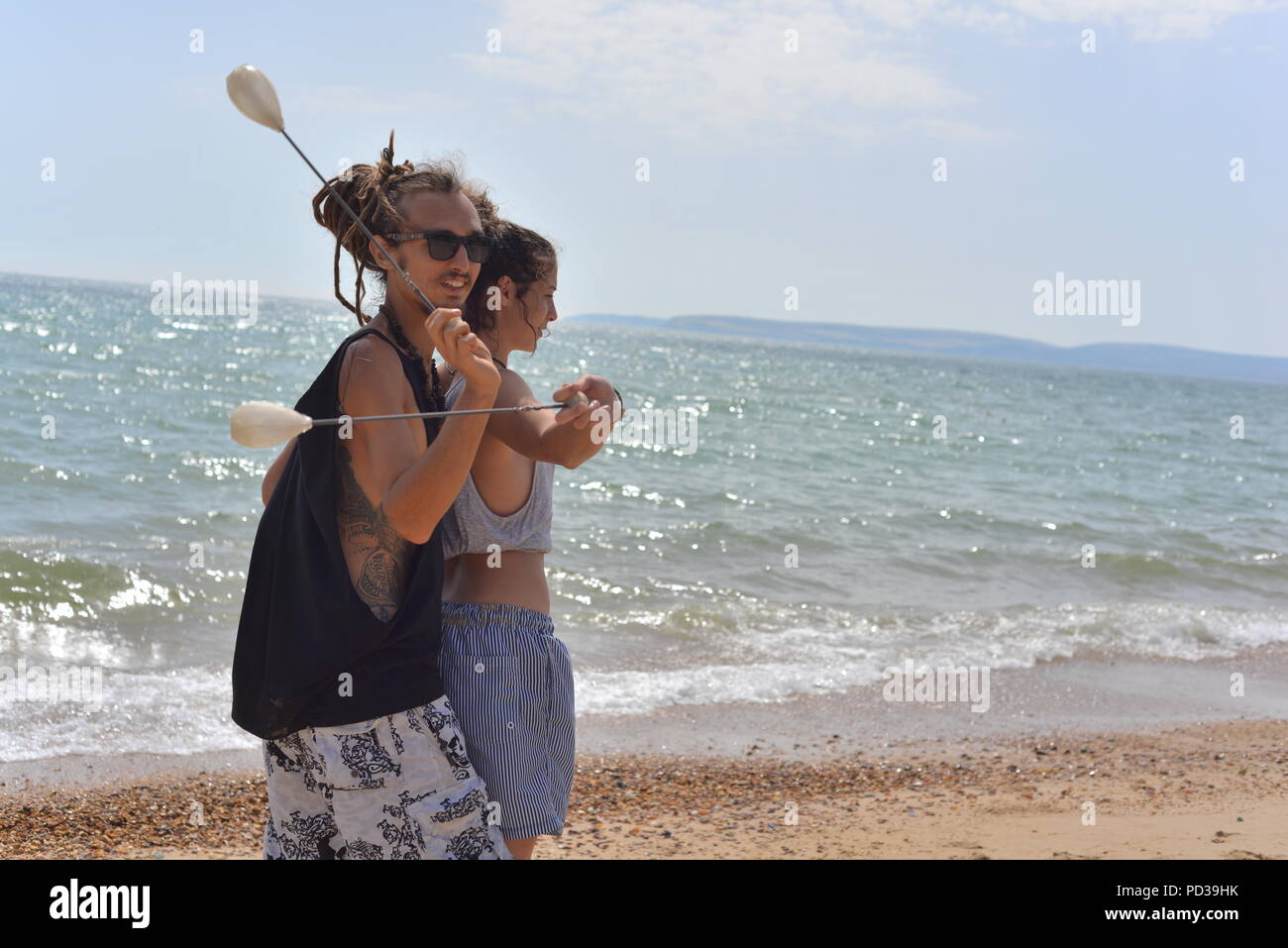 Coppia sorridente con una sfera e una stringa di terapia di coordinamento del gioco su una spiaggia lungomare in estate. Foto Stock
