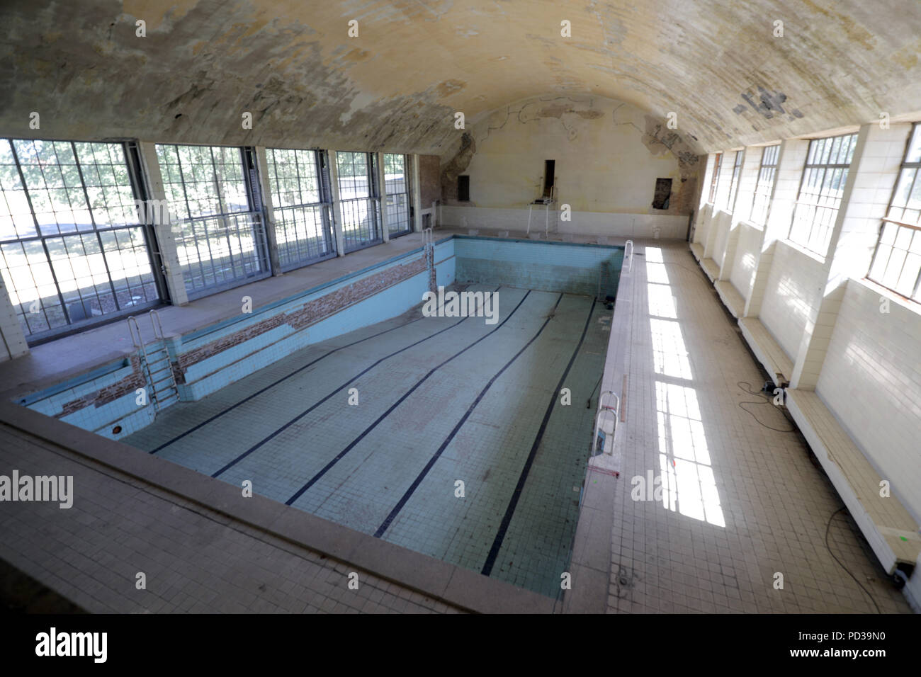 06.08.2018, Brandeburgo, Wustermark: le piastrelle sono scheggiati off nella piscina dell'ex villaggio olimpico dei Giochi Estivi del 1936. I lavori di ristrutturazione del villaggio su i limiti della città di Berlino sarà più costoso di quanto previsto in origine. "L'importo di 50 milioni di euro sarà certamente considerevolmente superato", ha detto un portavoce di terraplan. La società ha assunto una grande parte del sito. Foto: Wolfgang Kumm/dpa Foto Stock