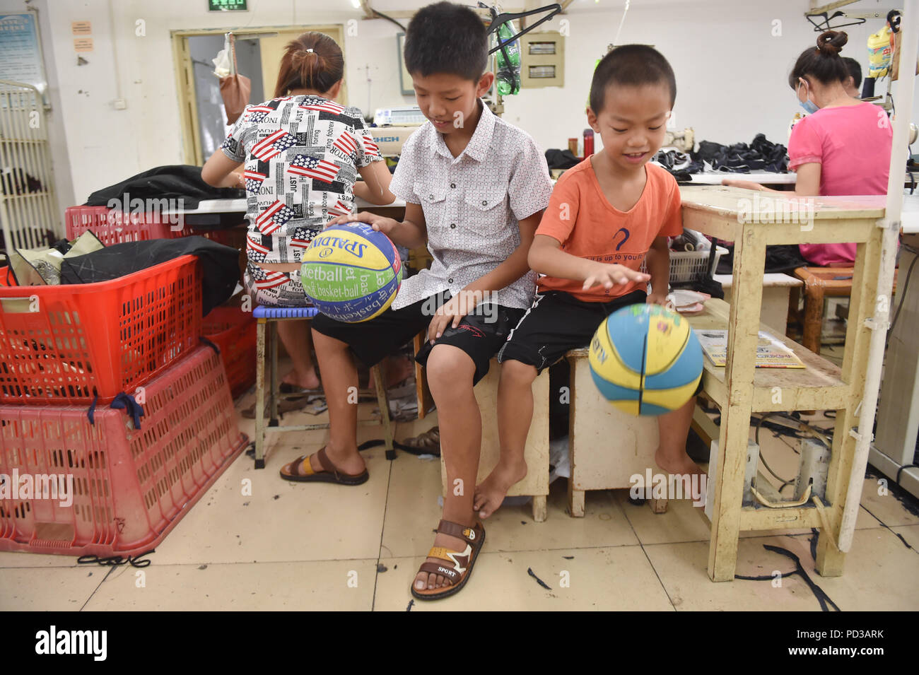 (180806) -- SHISHI, il 6 agosto 2018 (Xinhua) -- giocare i bambini con le palle in una fabbrica di abbigliamento mentre i loro genitori lavorano in Shishi City, a sud-est della Cina di provincia del Fujian, 31 luglio 2018. Shishi, un ben noto di produzione di capi di abbigliamento di base in Cina, saluta il picco stagionale per abbigliamento trasformazione durante le vacanze estive degli studenti. Che vivono e crescono nelle fabbriche di abbigliamento, figli di lavoratori locali trascorrere le loro vacanze con i loro genitori qui in un modo diverso. (Xinhua/canzone Weiwei) Foto Stock