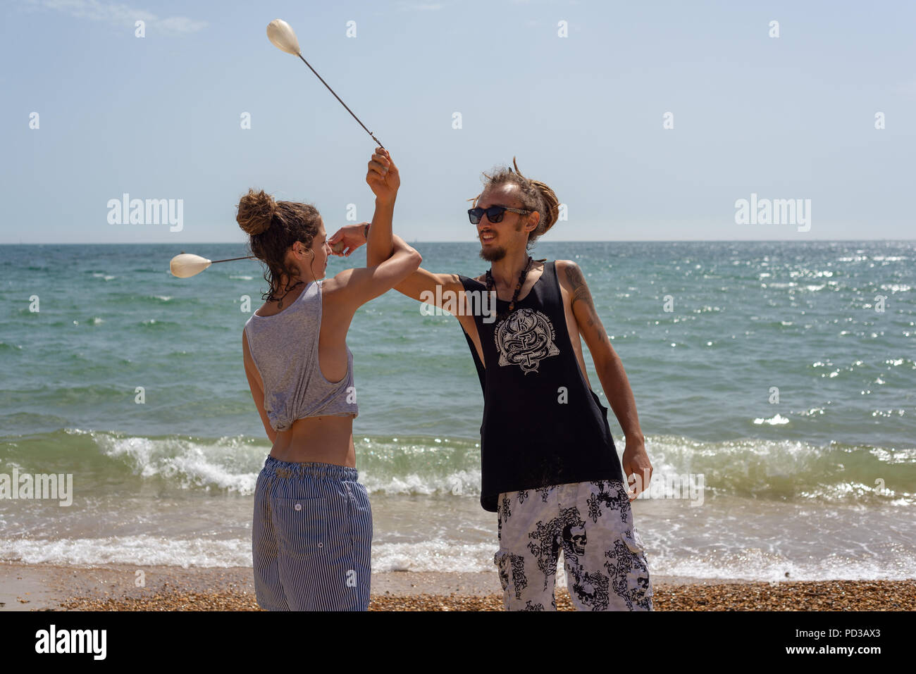 Giovani coppie che praticano la loro coordinazione interattiva e le loro abilità di giocoleria sulla spiaggia durante l'ondata di caldo estivo. Bournemouth, Dorset, Regno Unito, lunedì 6th agosto 2018 Foto Stock