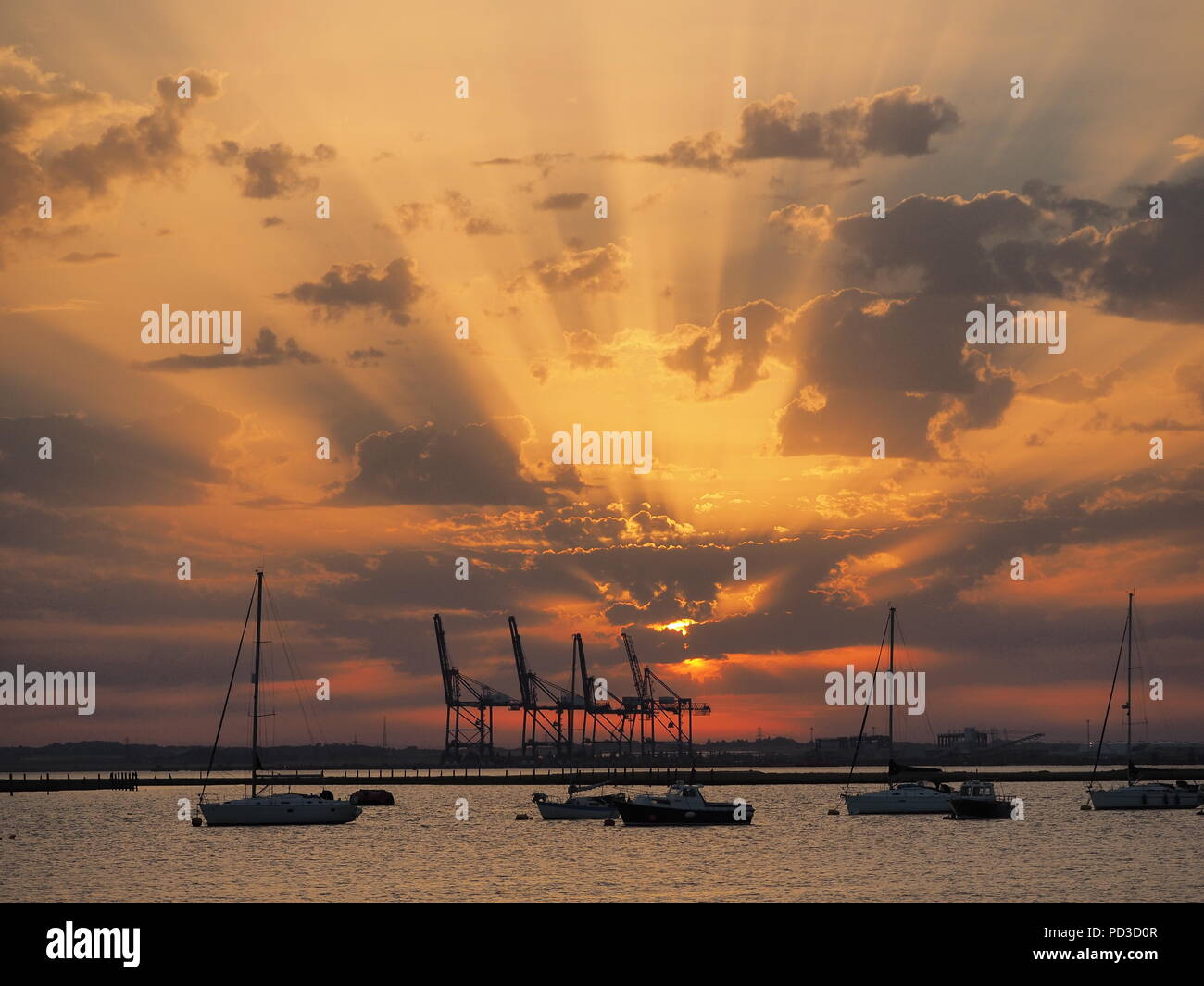 Queenborough, Kent, Regno Unito. Il 6 agosto, 2018. Regno Unito Meteo: il sole al tramonto, Queenborough, Kent. La gru di Thamesport sull'isola di Grain in distanza. Credito: James Bell/Alamy Live News Foto Stock