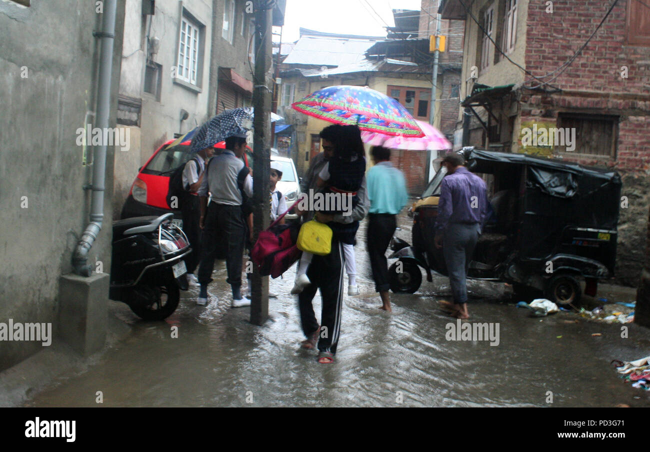 Srinagar, .KASHMIR .07.Agosto .i genitori ricevono la scuola dei bambini torna alla home gettare acqua strade di accesso dopo .un incantesimo pesanti di pioggia ha causato la registrazione di acqua in diverse aree disturbi veicolare e circolazione pedonale.pioggie causano l'acqua-logging in zone della città pendolari hanno dovuto affrontare un momento difficile dopo forti piogge hanno flagellato .diverse zone .Kashmir valle portando un po' di sollievo alle persone dopo tre giorni di caldo condizioni meteo.come per un dipendente in servizio meteorologico il Kashmir centrale sta a testimoniare la pioggia in condizioni di periodici su oggi.Le strade all'interno località a credito: sofi suhail/ Foto Stock