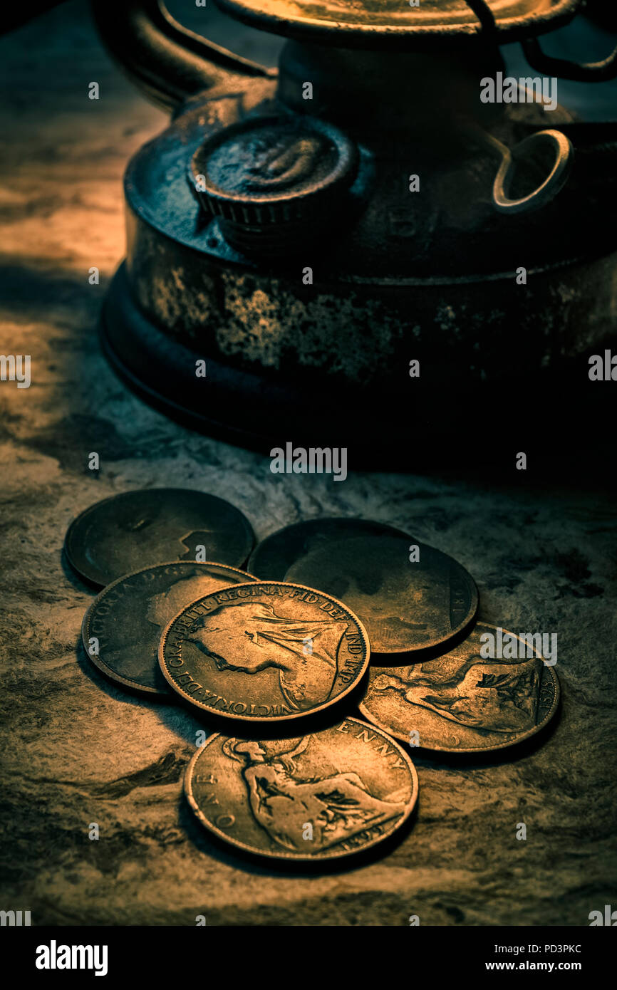 Vecchio British penny monete illuminato da una lampada ad olio. Foto Stock