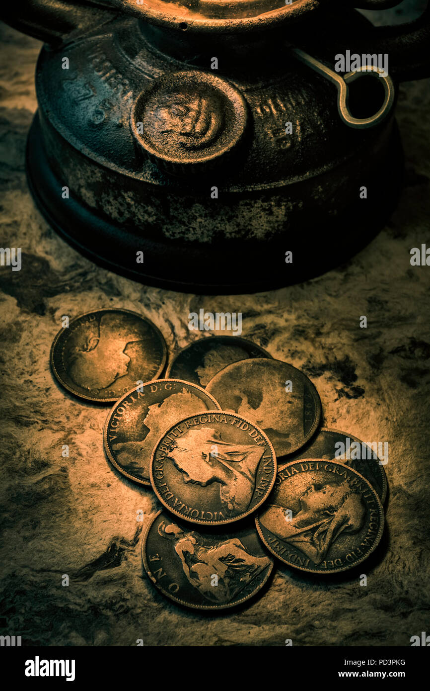 Vecchio British penny monete illuminato da una lampada ad olio. Foto Stock