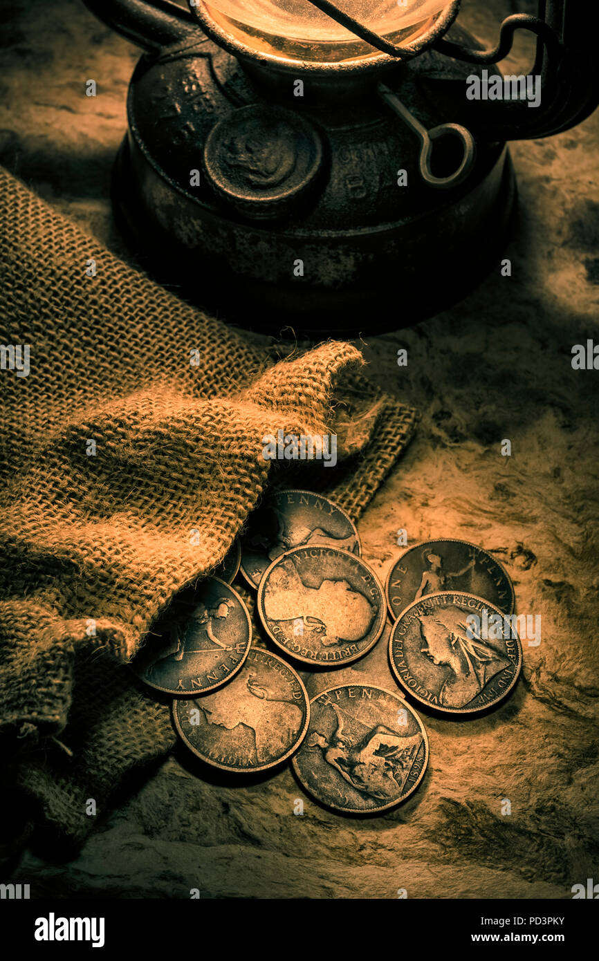 Vecchio British penny monete illuminato da una lampada ad olio. Foto Stock