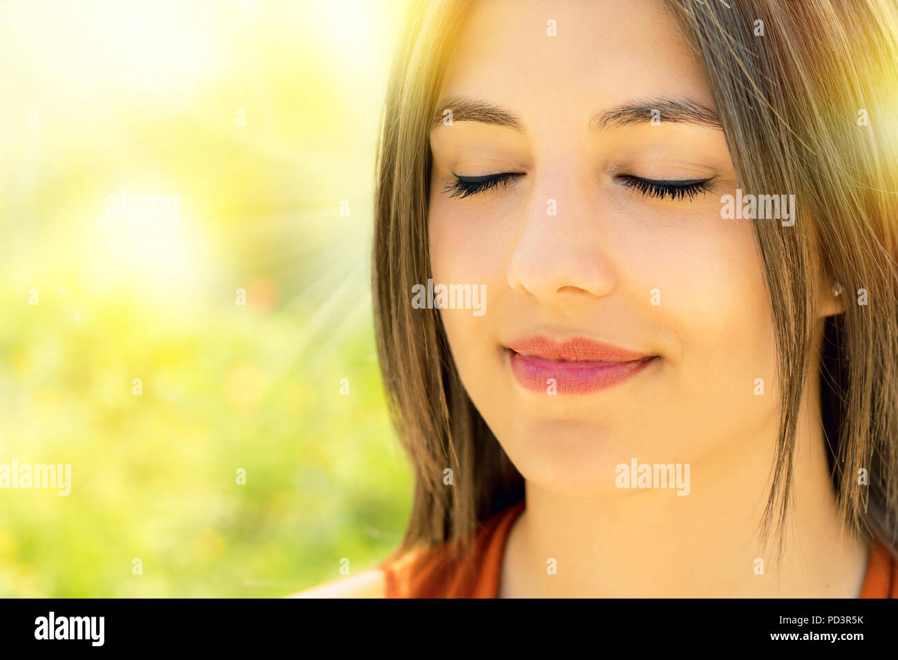 Close up ritratto di attraente rilassata giovane donna meditando all'aperto.la ragazza con gli occhi chiusi contro luminoso colorato sfondo all'aperto. Foto Stock