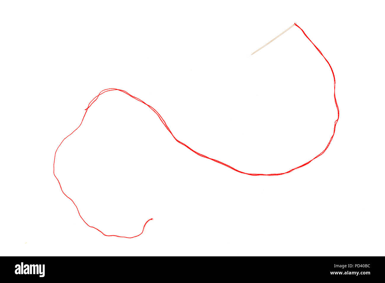 Una foto aerea di un ago con un filo rosso su sfondo bianco Foto Stock