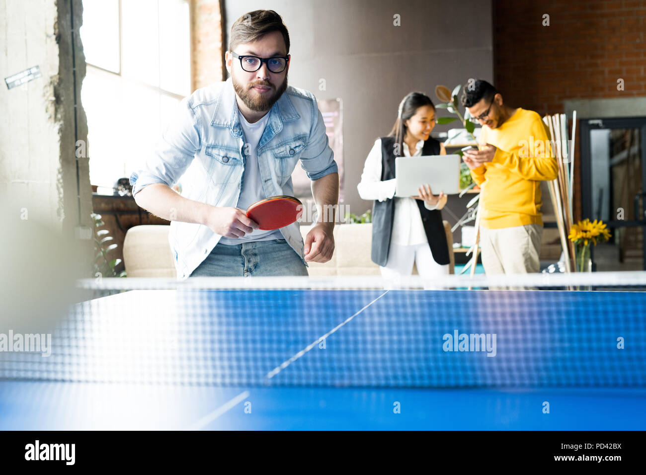 L'uomo giocando a ping-pong in Office Foto Stock