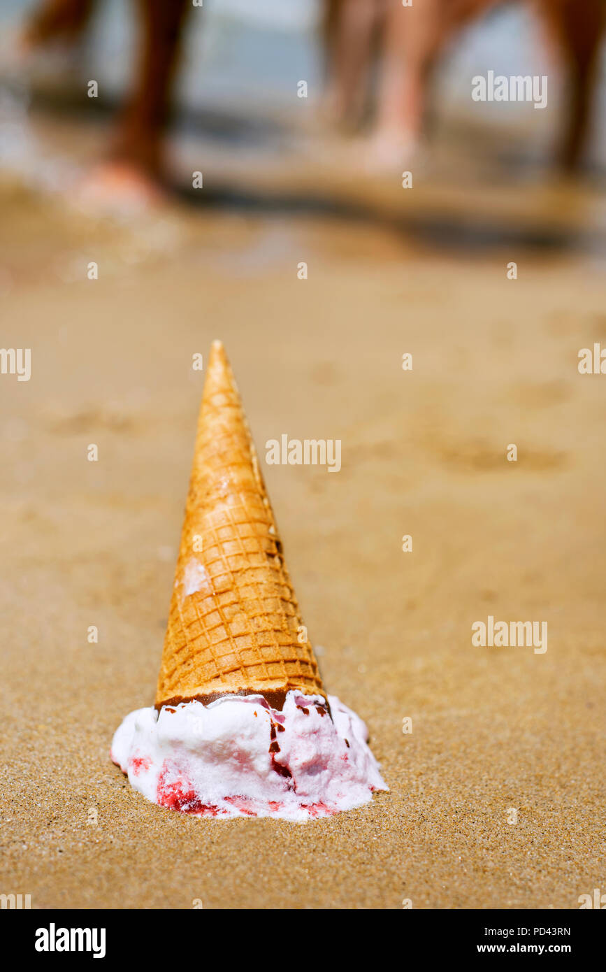 Primo piano di un cono gelato capovolto sceso sulla sabbia di una spiaggia Foto Stock