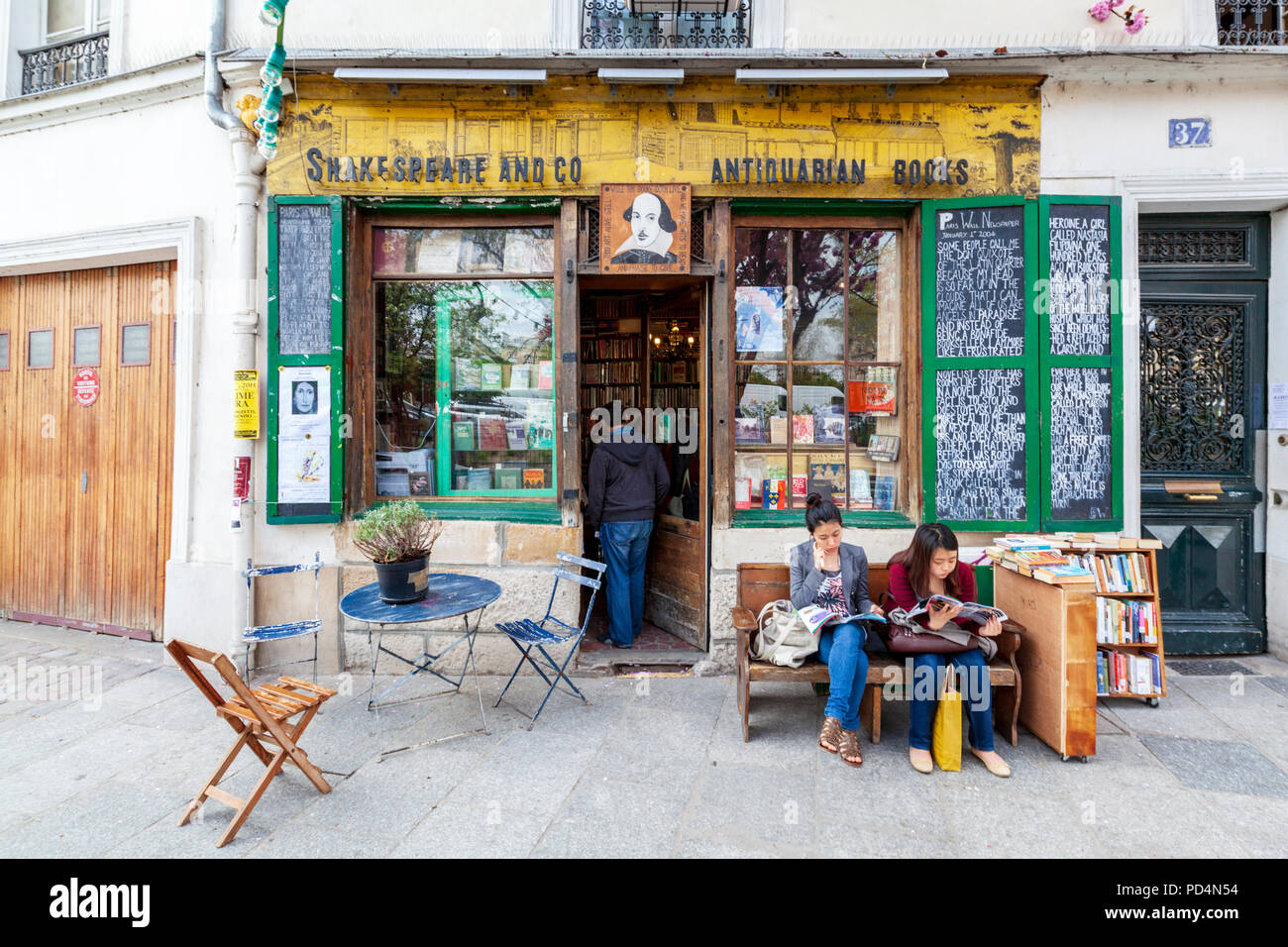 Due donne che leggono fuori dalla libreria Shakespeare and Company nel quartiere Latino di Parigi, Francia Foto Stock