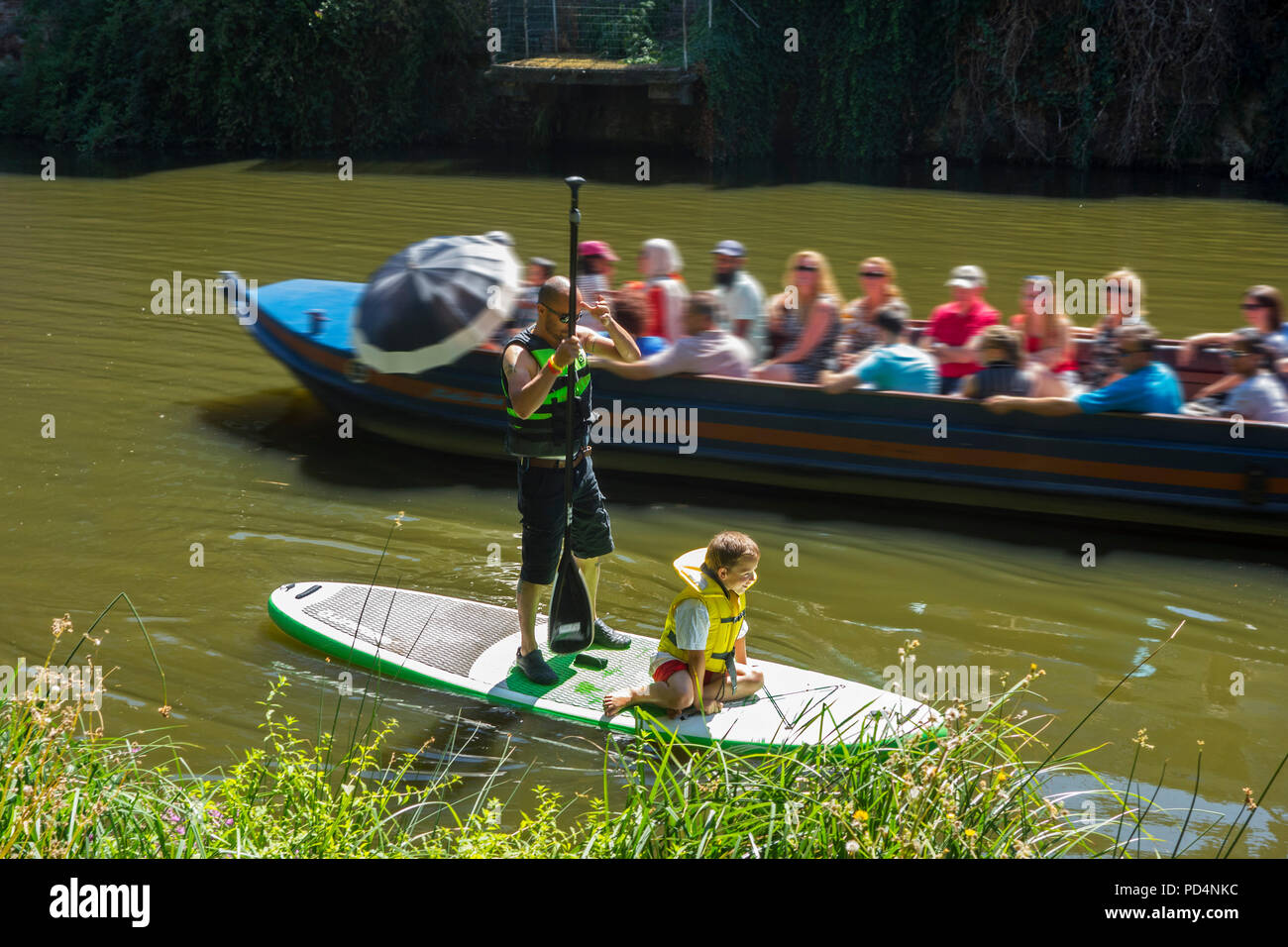 Barca con turisti di passaggio uomo con bambino su stand up paddle board / SUP nella città Mechelen / Malines, Anversa, Fiandre, in Belgio Foto Stock