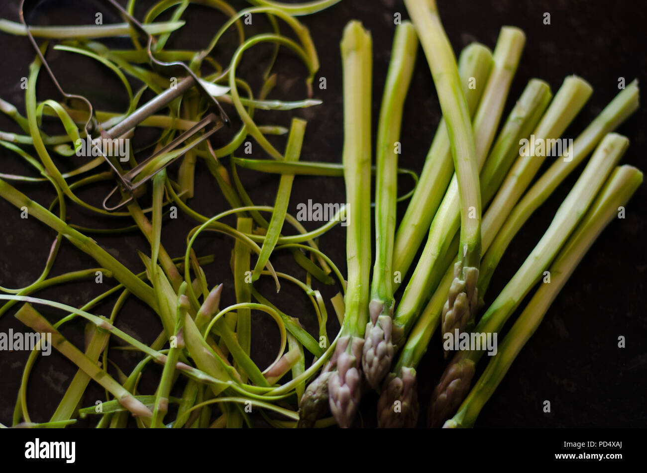 Sbucciate gli asparagi verdi su sfondo scuro. Foto Stock