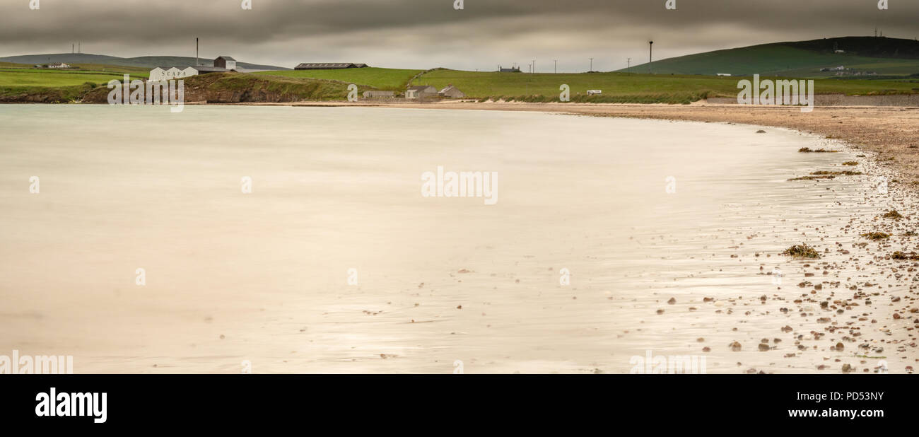 La Scapa baia vicino a Kirkwall nelle Orkney con la Scapa distillery edifici seduto sopra il litorale in distanza. Foto Stock