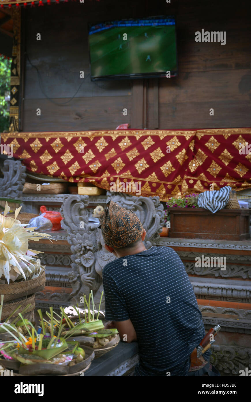 Uomo di guardare la televisione in pura Dalem, tempio indù in Ubud, Bali. Indonesia. Foto Stock