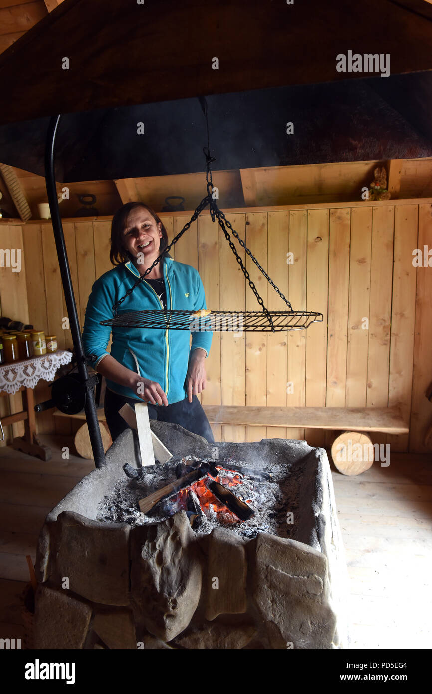 Donna fumatori e Oscypek Golka formaggio tradizionale da montagne polacche nel villaggio Witow, Tatra County, vicino a Zakopane, Polonia Foto Stock