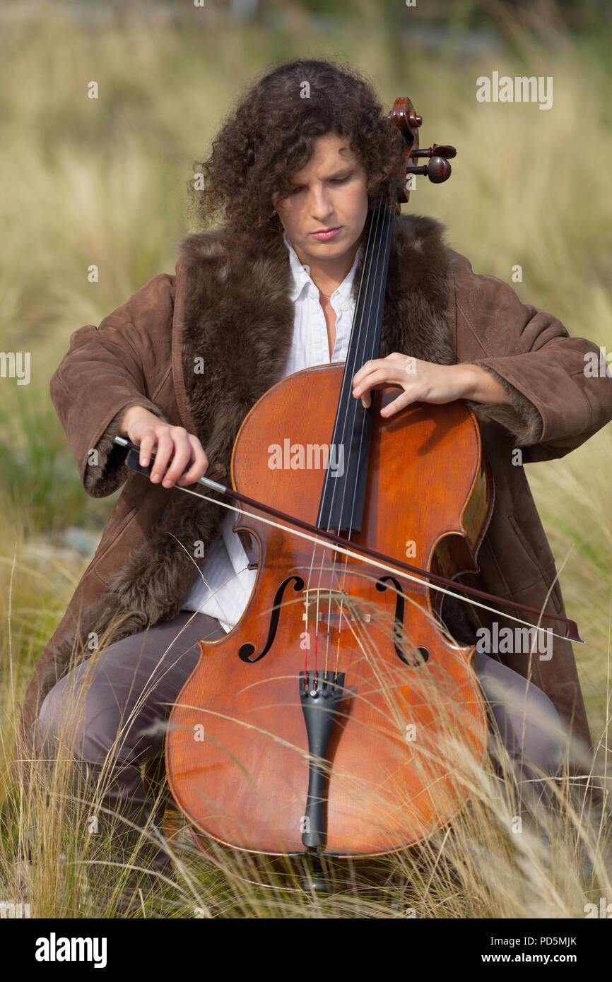 Donna che gioca il violoncello tra i campi Foto Stock