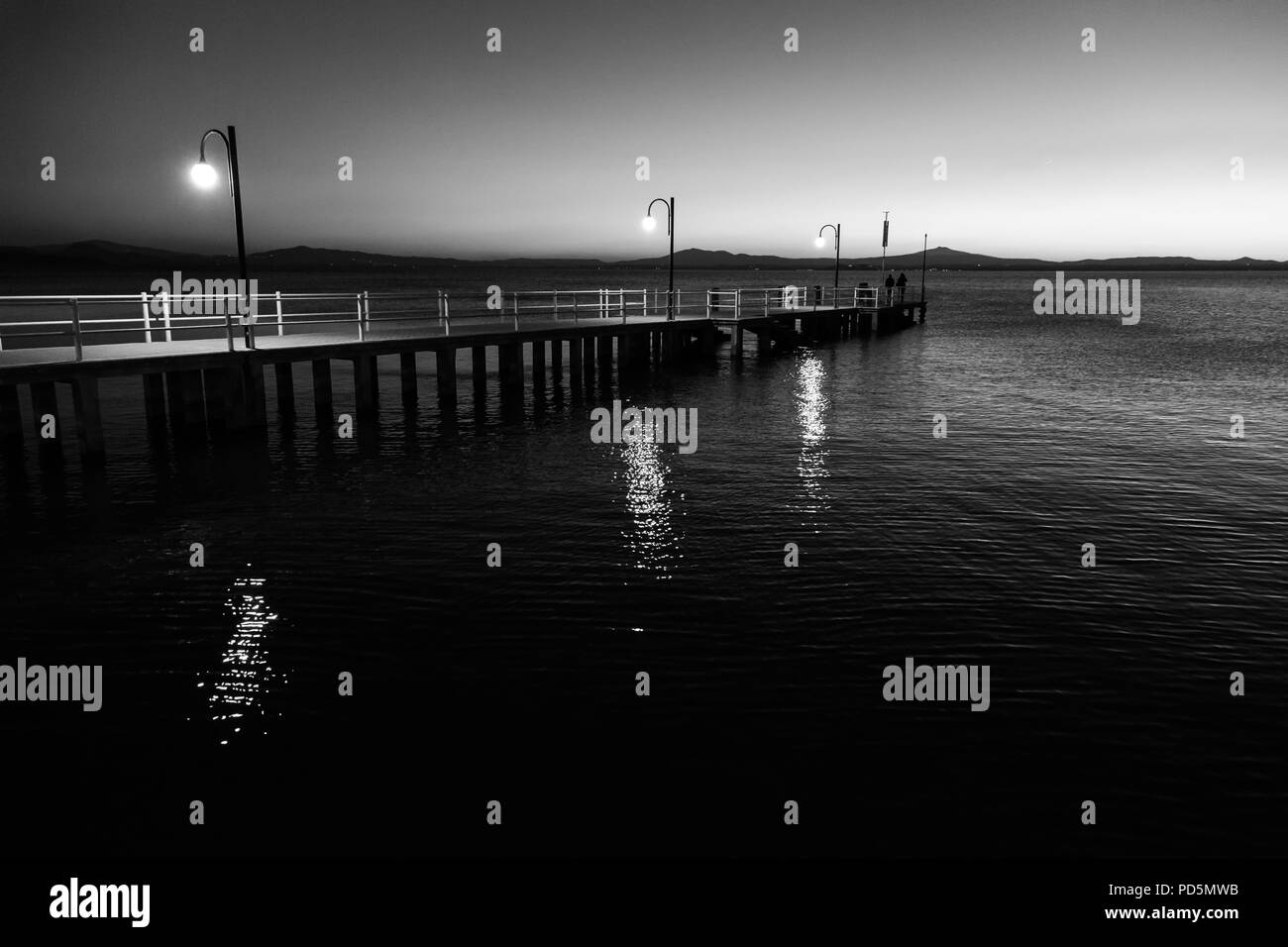 Alcune persone su un molo presso il lago Trasimeno (Umbria, Italia) al tramonto Foto Stock