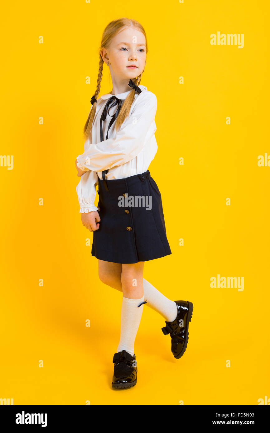 Ragazza con pigtail di colore rosso su sfondo giallo. Una bella ragazza è in piedi con il suo piede. Foto Stock