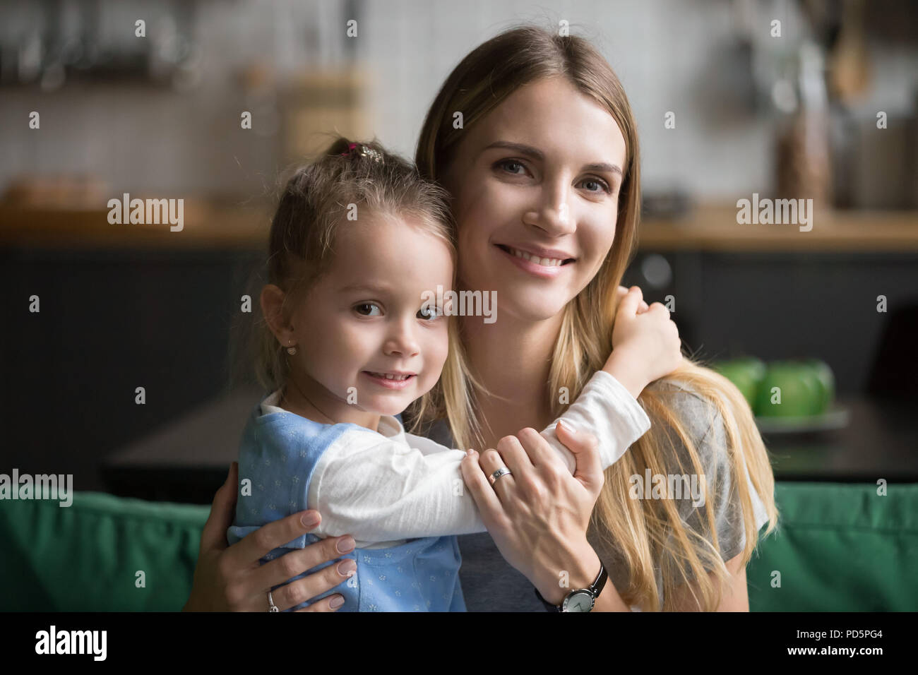 Sorridente mom abbracciando carino adottato kid figlia guardando camer Foto Stock