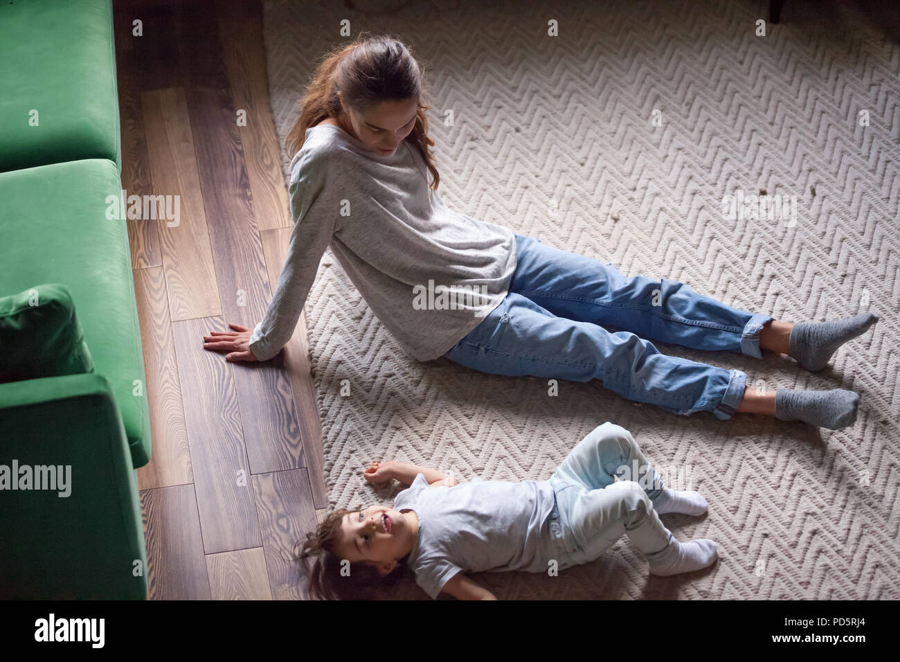 Carino kid ragazza distesa sul pavimento caldo rilassante con MOM Foto Stock
