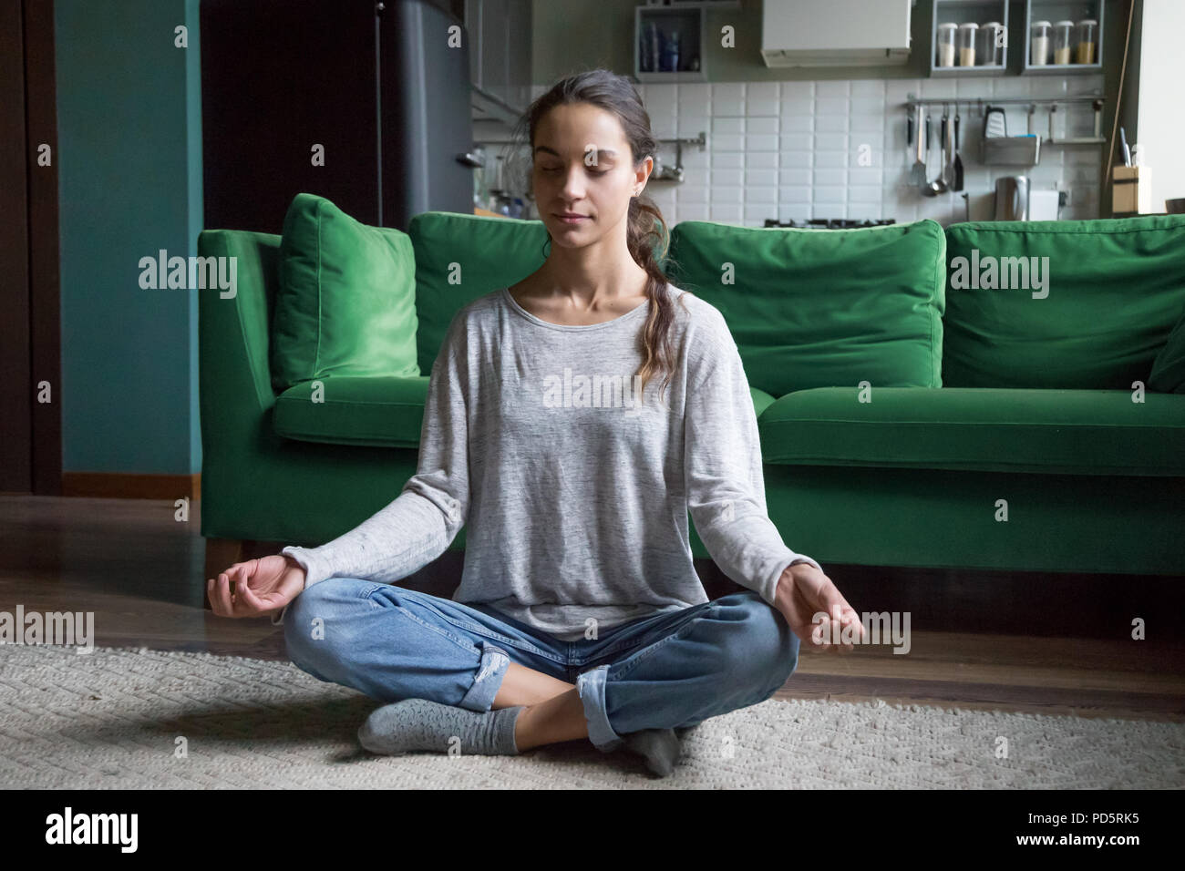 Calma donna seduta in lotus pongono la pratica di meditazione a casa Foto Stock