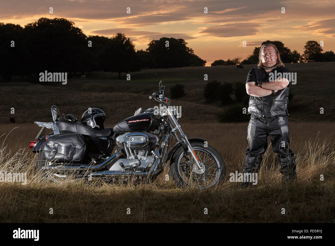 Rivestito in pelle biker in posa per un servizio fotografico sul suo custom Harley Davidson XL883 Sportster basso cruiser motociclo, sul Beverley westwood, East Riding Foto Stock