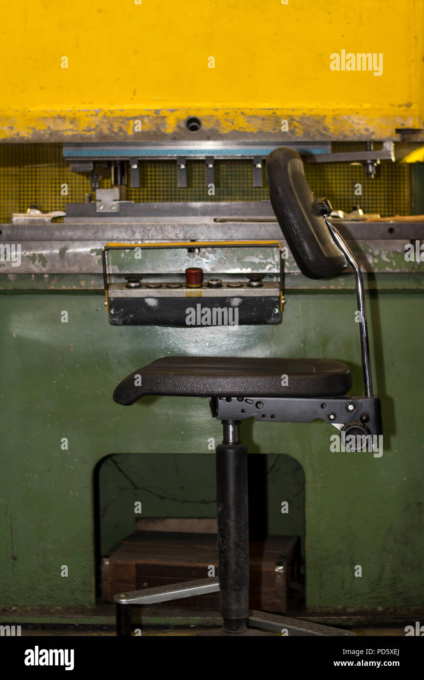 Vecchio rustico vintage giallo retrò parte macchina costruzione meccanica premere per lamiera in acciaio forte trasformazione premere seduta area di lavoro Foto Stock